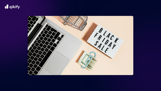 Laptop with 'Black Friday Sale' sign and money on a beige surface, branded with Qikify.