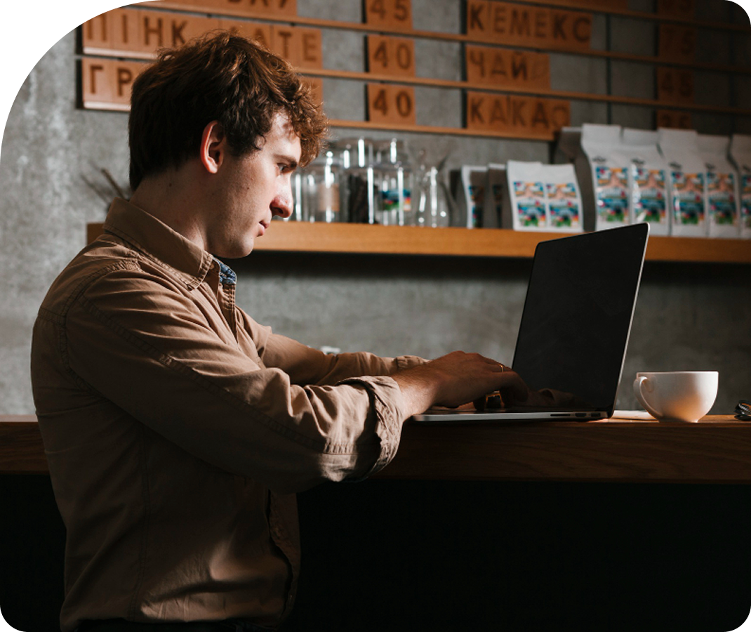 Man using a laptop at a table with a cup in the table